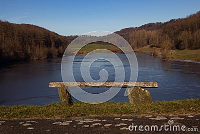 Tilted old empty bench at a lake Stock Photo