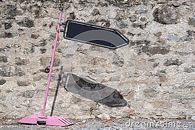 Tilted pink road sign with black board arrow showing direction. Wall background in sunny day. Stock Photo