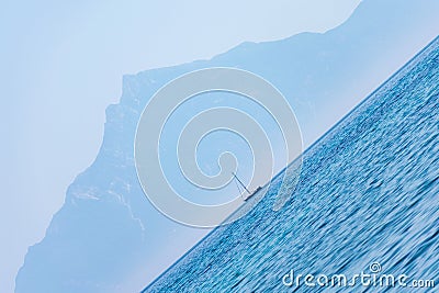 Tilted view of a sailboat on the horizon, with mount Athos looming in the background in Chalkidiki, Greece Stock Photo