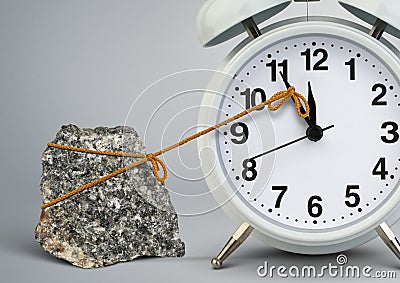 Time on alarm clock stop by stone, delay concept Stock Photo