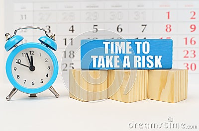 Against the background of the calendar, an alarm clock and a blue block with the inscription - Time to Take a Risk Stock Photo