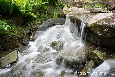 Time exposure photo shot with a small waterfall over rocks in a stream and milky blurred water Stock Photo