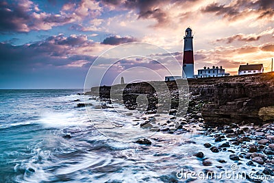Time lapse sunset on coast with lighthouse on cliffs Stock Photo