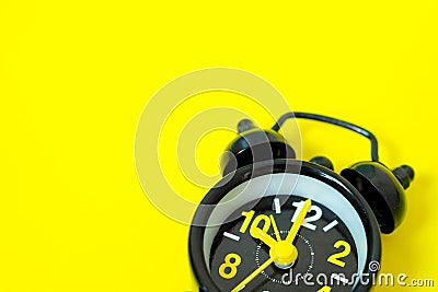 Vintage black alarm clock Isolated on yellow background With space for design Stock Photo