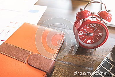 Time management concept, Alarm clock,notebooke and computer laptop on wooden table in office. Stock Photo