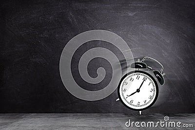 Retro black alarm clock alerting at seven o`clock on chalkboard background. Stock Photo