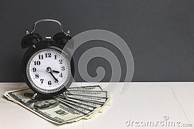 Time and money. Dollars cash. Retro alarm clock and cash money on table. Stock Photo