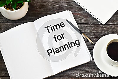 Time for planning. Green plant, a cup of coffee next to a pen and a notebook that says TIME TO PLANNING on a wooden table. Flat la Stock Photo