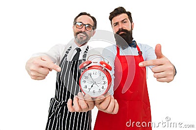 Time to cook. Men pointing at alarm clock. Man bearded hipster and mature chef apron white background. Cook dinner. We Stock Photo