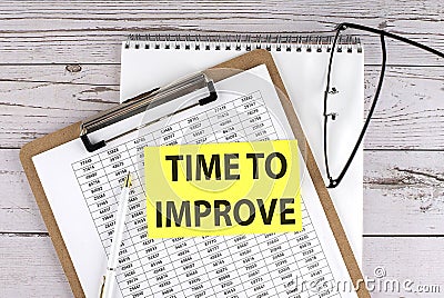 TIME TO IMPROVE text on yellow sticky on clipboard with chart, wooden background Stock Photo