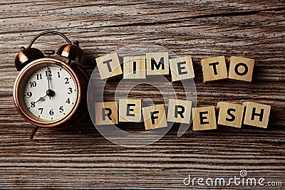 Time To Refresh alphabet letter with alarm clock on wooden background Stock Photo