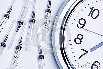 Syringes of vaccine and alarm clock. Medicine concept. Stock Photo