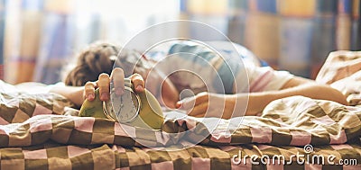 Time to wake up, sleeping lying in bed man beats the alarm clock in the morning f Stock Photo