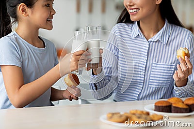 Time for vitamins. Asian girl and her young mother drinking milk in kitchen, enjoying calcium drink, closeup, crop Stock Photo