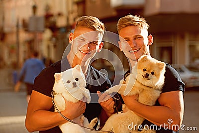 Time for a walk. Muscular men with dog pets. Twins men hold pedigree dogs. Happy twins with muscular look. Spitz dogs Stock Photo