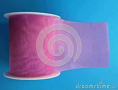 Purple gift wrapping ribbon over blue background. Stock Photo