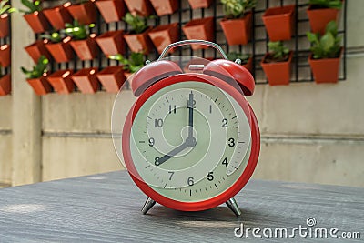 Timeliness concept red round clock at 8 o`clock with vertical garden background Stock Photo
