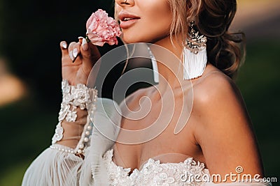 Times in a woman`s hand, she takes a rose, bride`s fees, morning bride, white dress, put on earrings Stock Photo
