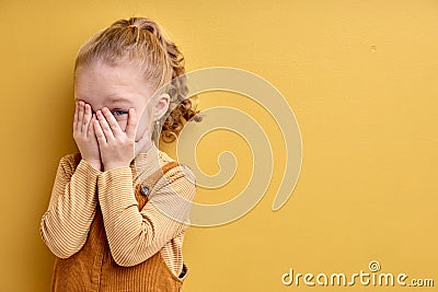 Timid little girl being shy, covering eyes. Cute female child kid playing seek and hide Stock Photo