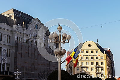 Timisoara, Romania, February 26, 2020; the flags of Romania on a floor lamp on which are placed several pigeons, and in the back Editorial Stock Photo