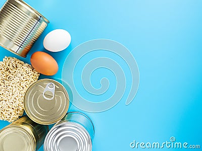 Tin cans, macaroni, eggs on a blue background, copispace, mock up. Stocks of fast food and long-term storage during the Stock Photo