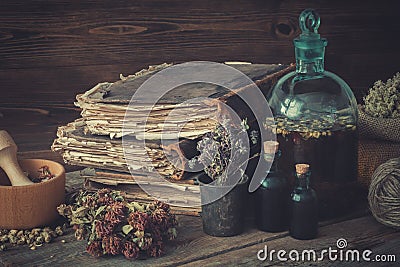 Tincture bottles, assortment of dried healthy herbs, old books, wooden mortar, sack of medicinal herbs. Herbal medicine. Stock Photo