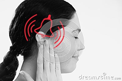 Tinnitus. A dissatisfied young woman holds her hand over her ears, experiencing ringing and pain. The concept of ear Stock Photo