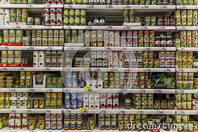 Tins of canned food on the shelves in the supermarket. Big choice. Front view. Blurred Editorial Stock Photo