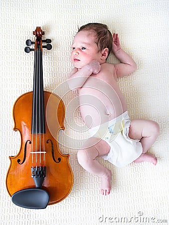 Tiny newborn girl lying next to a violin Stock Photo