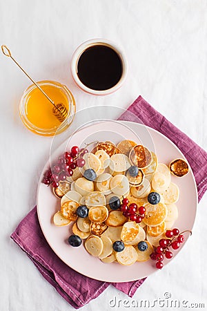 Tiny pancakes with berries, honey, coffee. Pancake cereal. The concept of Breakfast, food trends. Copy space Stock Photo