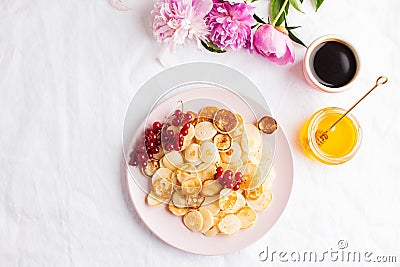 Tiny pancakes with berries, honey, flowers, coffee. Pancake cereal. The concept of Breakfast, food trends. Copy space Stock Photo