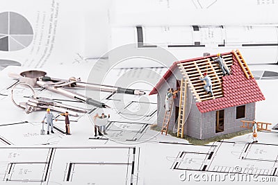 Tiny people build houses for architectural plans. The concept of Stock Photo