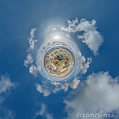 tiny planet in sky with clouds overlooking skyscrapers in new modern residential complex with high-rise buildings in town. Stock Photo