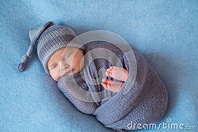 Tiny Sleeping Newborn Baby covered with rich purple coloured wrap Stock Photo
