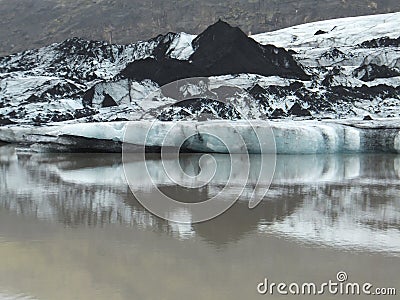 Tip of SÃ³lheimajÃ¶kull glacier in iceland, with dark layers of soil, reflected in water Stock Photo