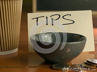 Tipping bowl in coffee shop with coins and coffee cup Stock Photo