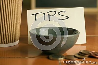 Tipping bowl in coffee shop with coins and coffee cup Stock Photo