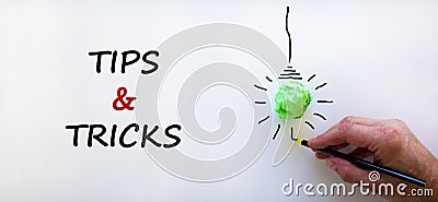 Tips and tricks symbol. Businessman writing words `Tips and tricks`, isolated on beautiful white background. Light bulb icon. Stock Photo