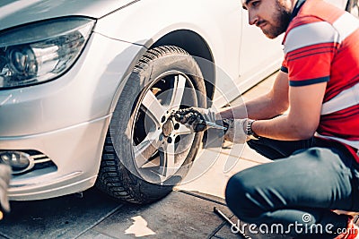 Tire maintenance, damaged car tyre or changing seasonal tires using wrench. Changing a flat car tire on the sideroad or in the cou Stock Photo