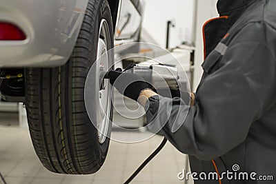 Tire service. Mechanic attaches the wheel to the car Stock Photo