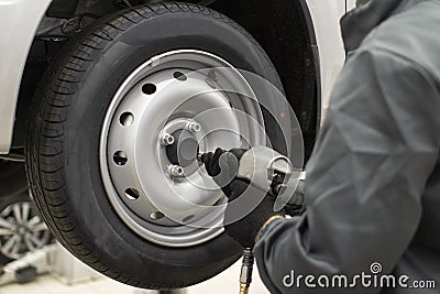 Tire service. Mechanic attaches the wheel to the car Stock Photo