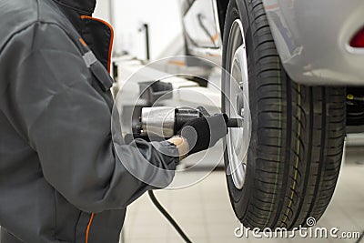 Tire service. Mechanic attaches the wheel to the car Stock Photo