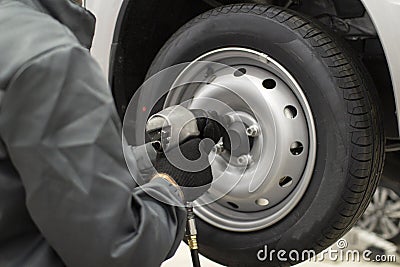 Tire service. Mechanic attaches the wheel to the car Stock Photo