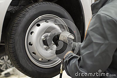 Tire service. Mechanic attaches the wheel to the car Stock Photo