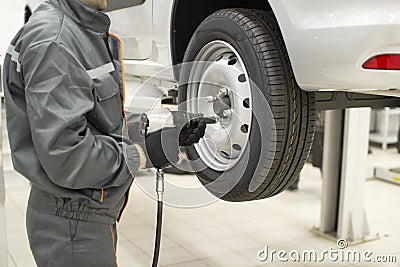 Tire service. Mechanic attaches the wheel to the car Stock Photo