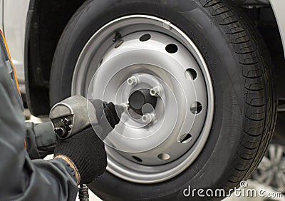 Tire service. Mechanic attaches the wheel to the car Stock Photo