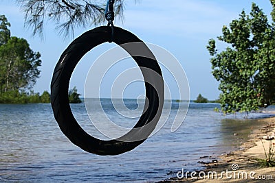 Tire swings hang from trees on the sandy beach with selective focus. Stock Photo