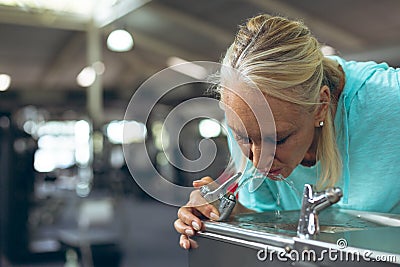 Tired active senior woman drinking tap water in fitness center Stock Photo