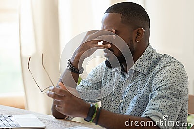 Tired african american businessman holding glasses feeling eye strain Stock Photo