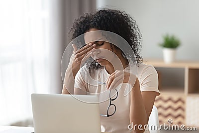 Tired African American woman taking off glasses, feeling eye strain Stock Photo